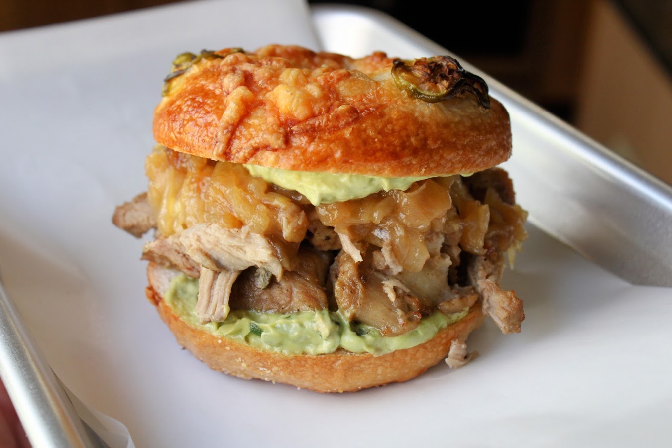 Carnitas and caramelized onion bagel sandwich